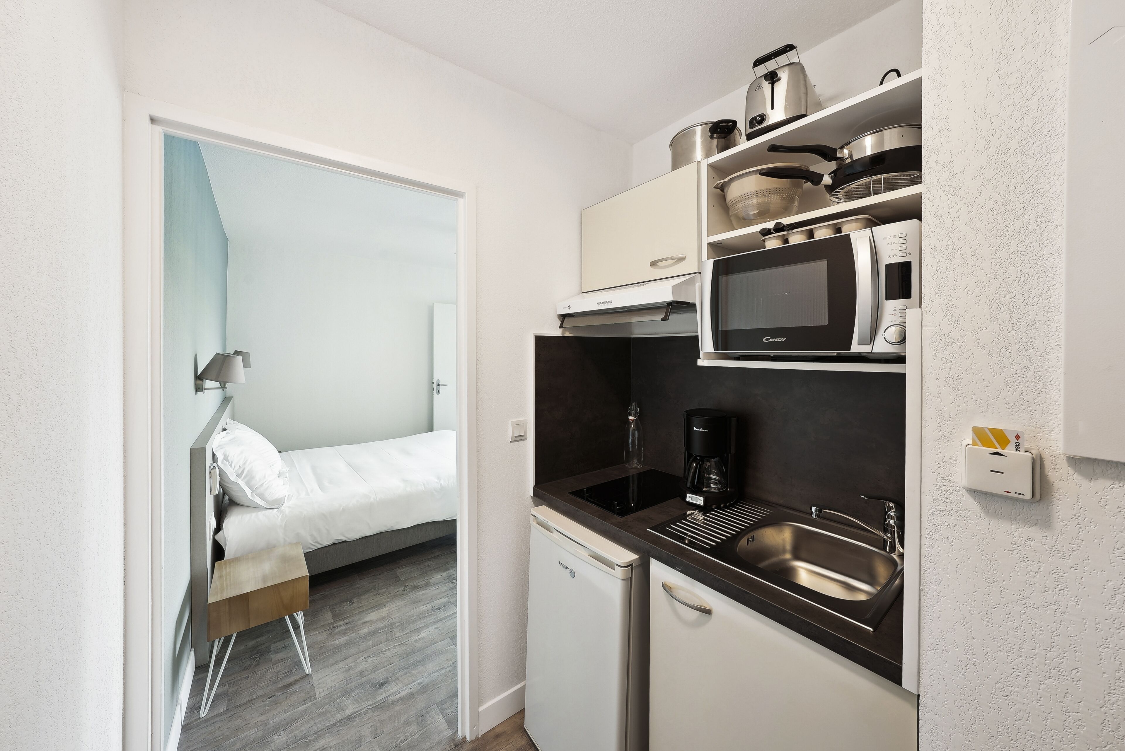 A compact kitchenette with a microwave, coffee maker, and a small refrigerator.