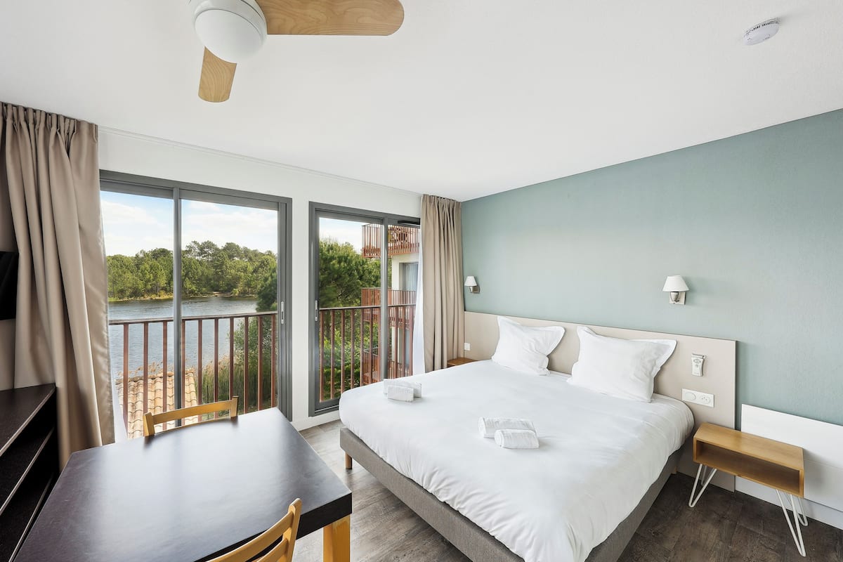 A hotel room with a large bed, a desk, and a view of a lake.