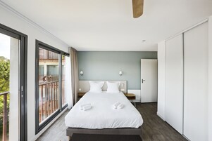 Habitación de hotel moderna con una cama grande, un balcón y vistas a la ciudad.