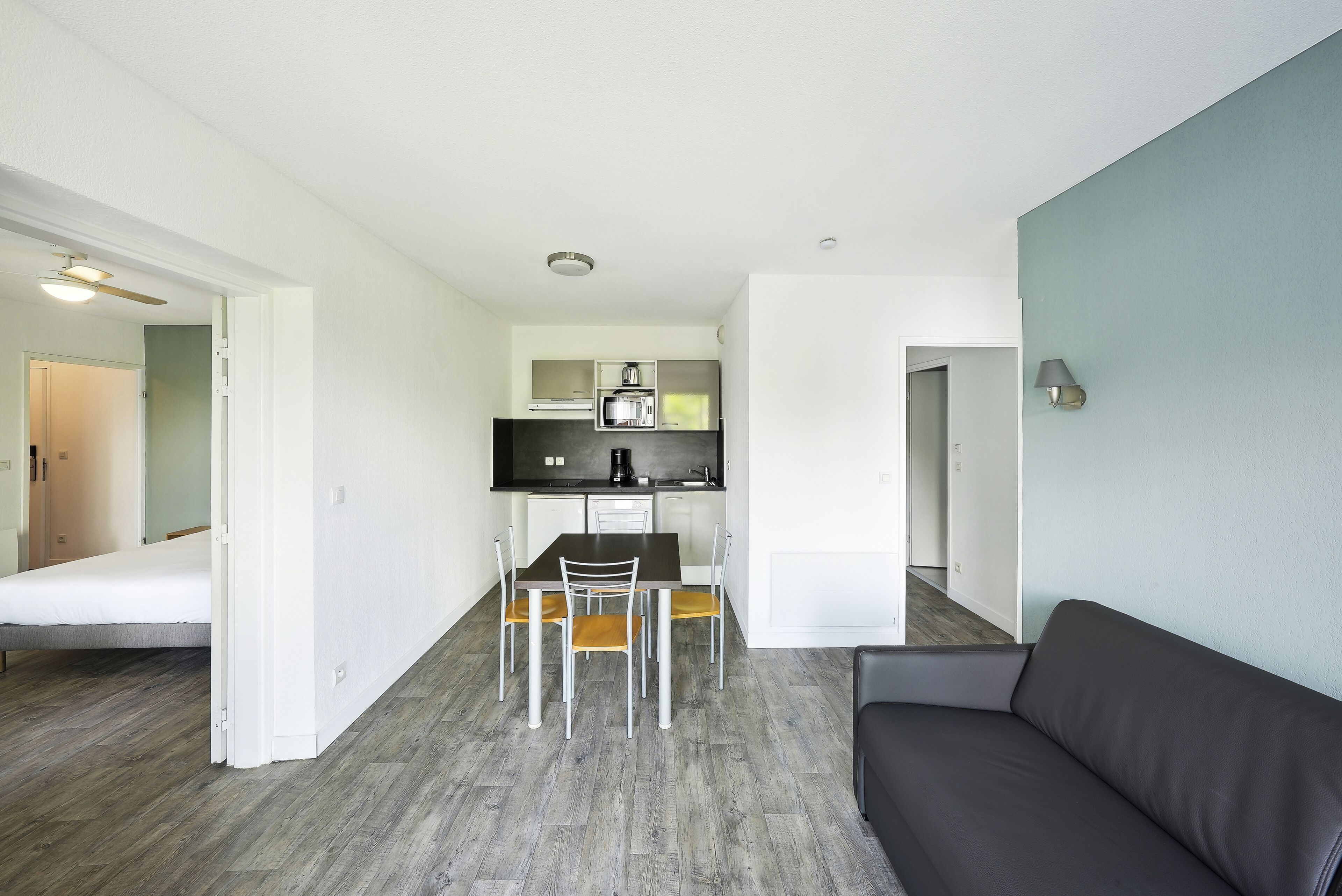 A compact living space with a kitchenette, a dining area, and a sofa.