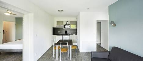 Un espacio habitable compacto con kitchenette, zona de comedor y sofá.