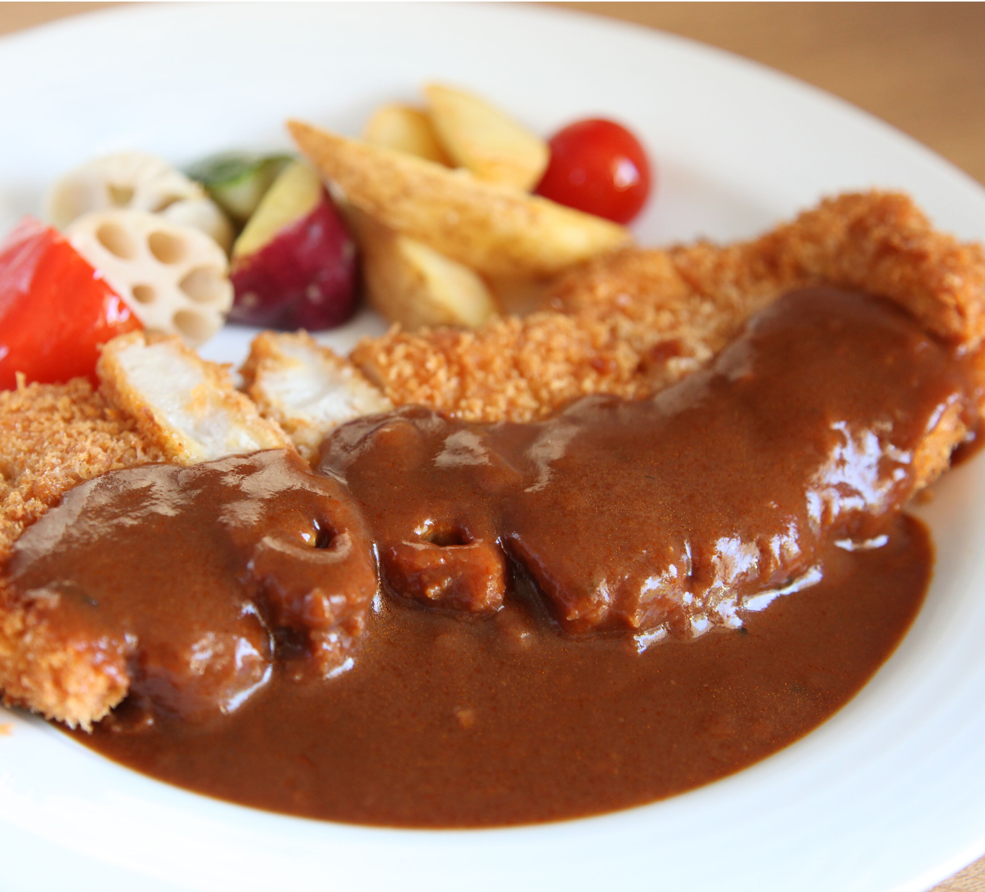 A plate with breaded cutlet, gravy, fries, and vegetables.
