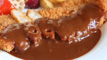 A plate with breaded cutlet, gravy, fries, and vegetables.