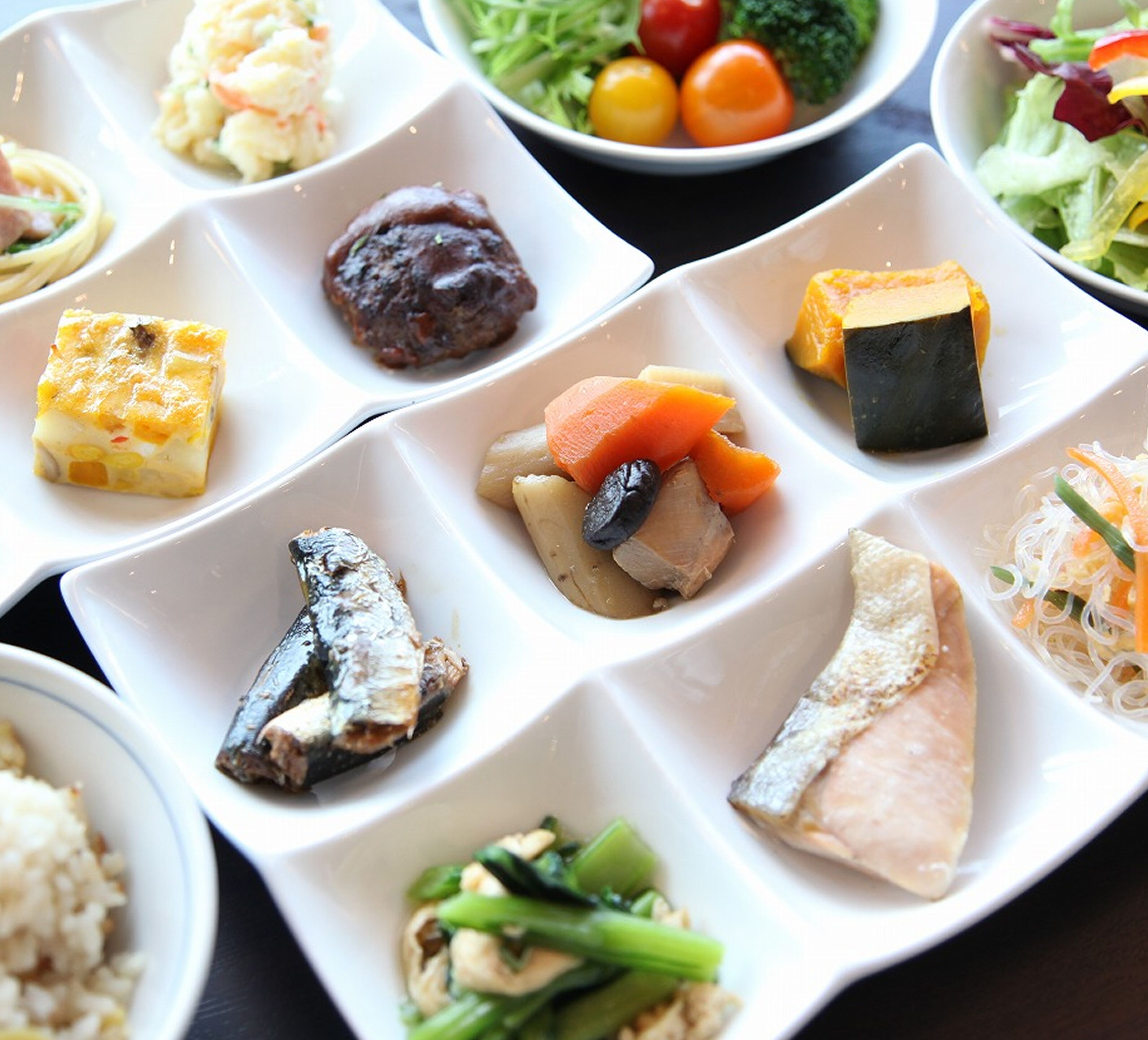 A variety of dishes arranged on a table, including seafood, vegetables, and a dessert.