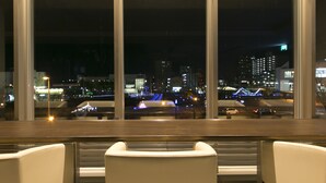 Vista da janela com vários painéis, com vista para um horizonte noturno com edifícios iluminados e uma ponte.