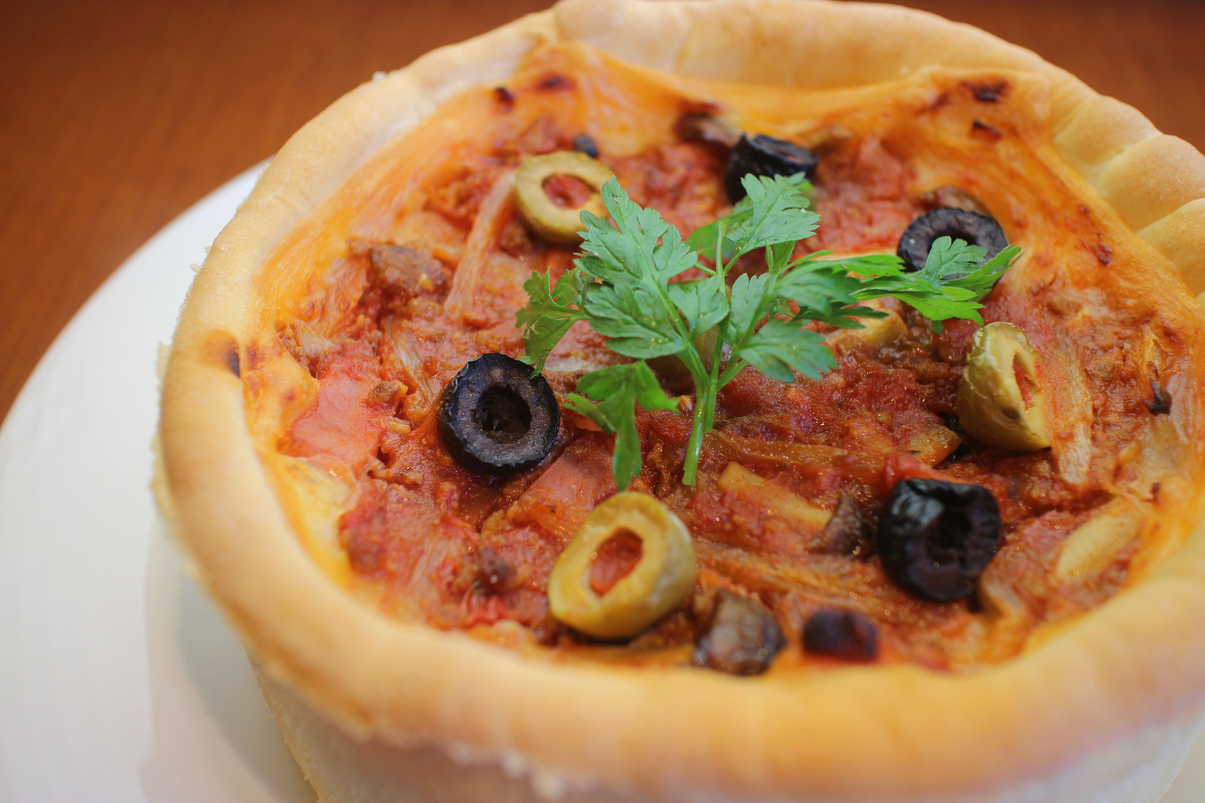 A pizza with a crusty edge, topped with black olives, green olives, and parsley.