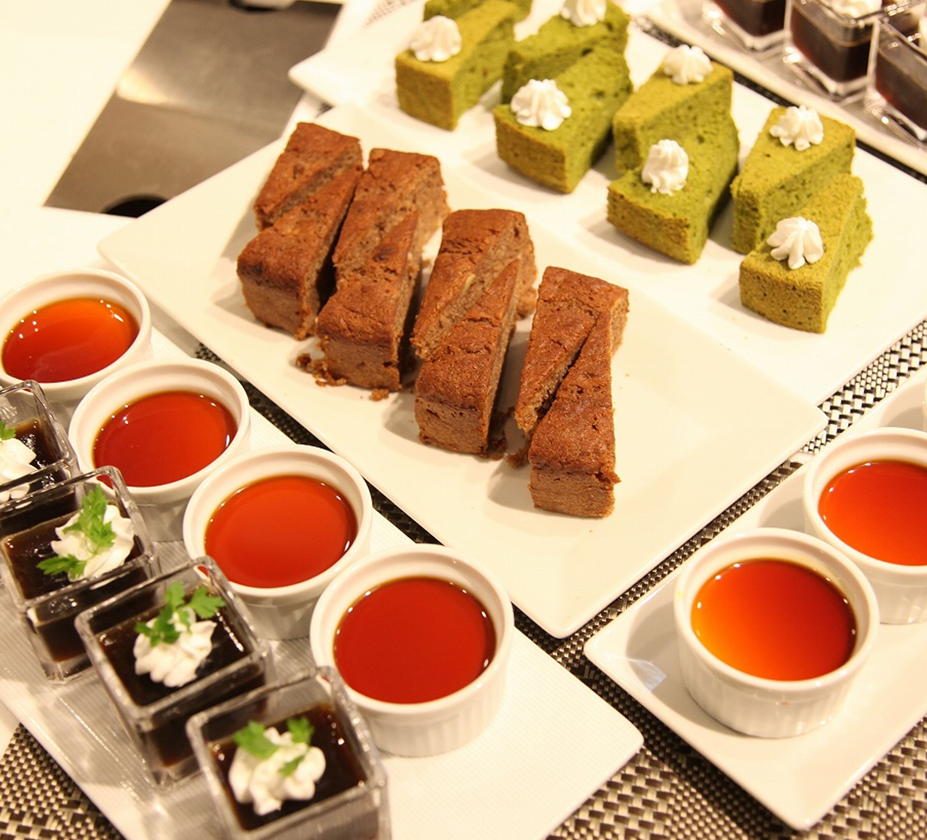 A dessert platter with various types of cakes and small bowls of sauce.