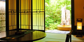 A traditional Japanese room with tatami flooring, a low table, a sliding door with a view of a bamboo garden, and a lantern. - Miyako (Gero)