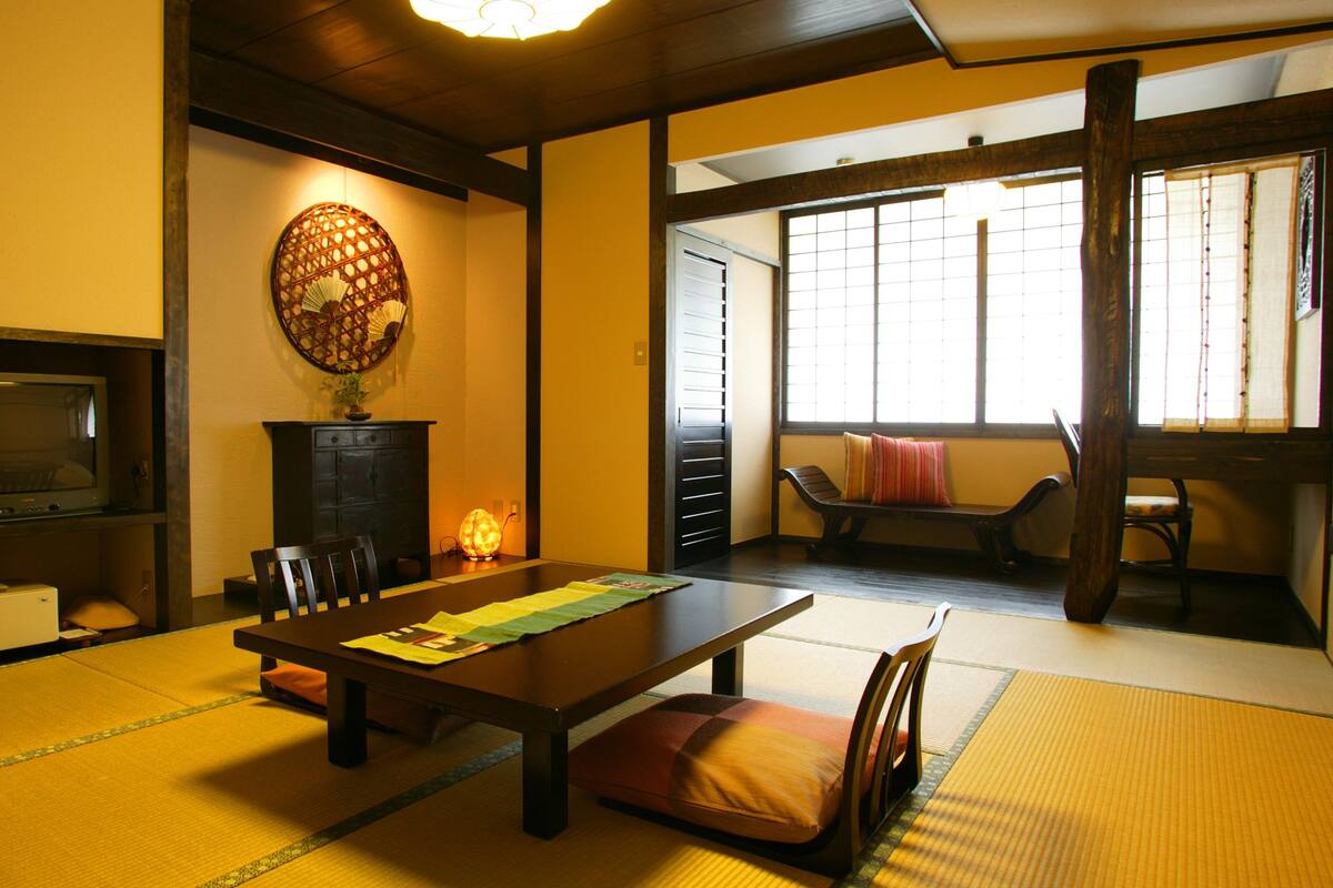 Une pièce de style japonais traditionnel, avec un sol recouvert de tatamis, une table basse et une porte coulissante donnant sur une autre pièce.