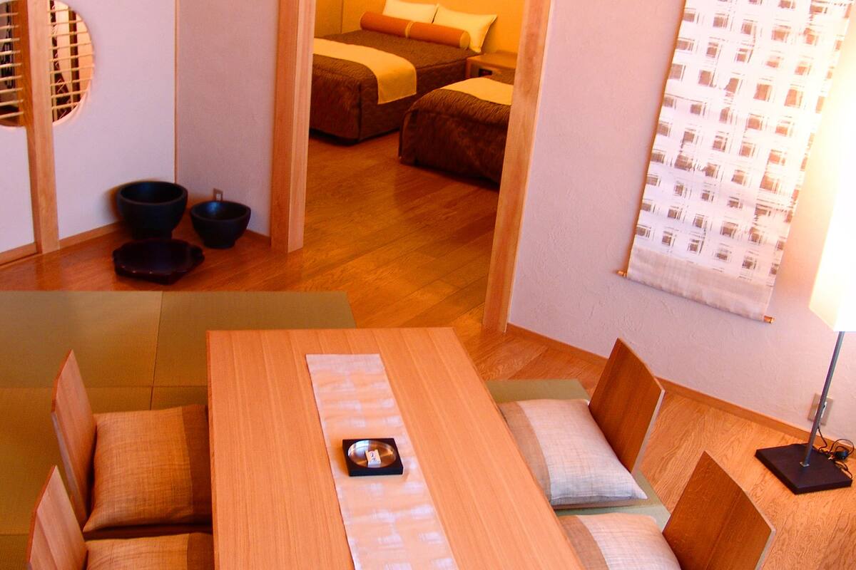 Une pièce de style japonais traditionnel, avec un sol recouvert de tatamis, une table basse avec des coussins et une porte coulissante ornée de motifs circulaires.