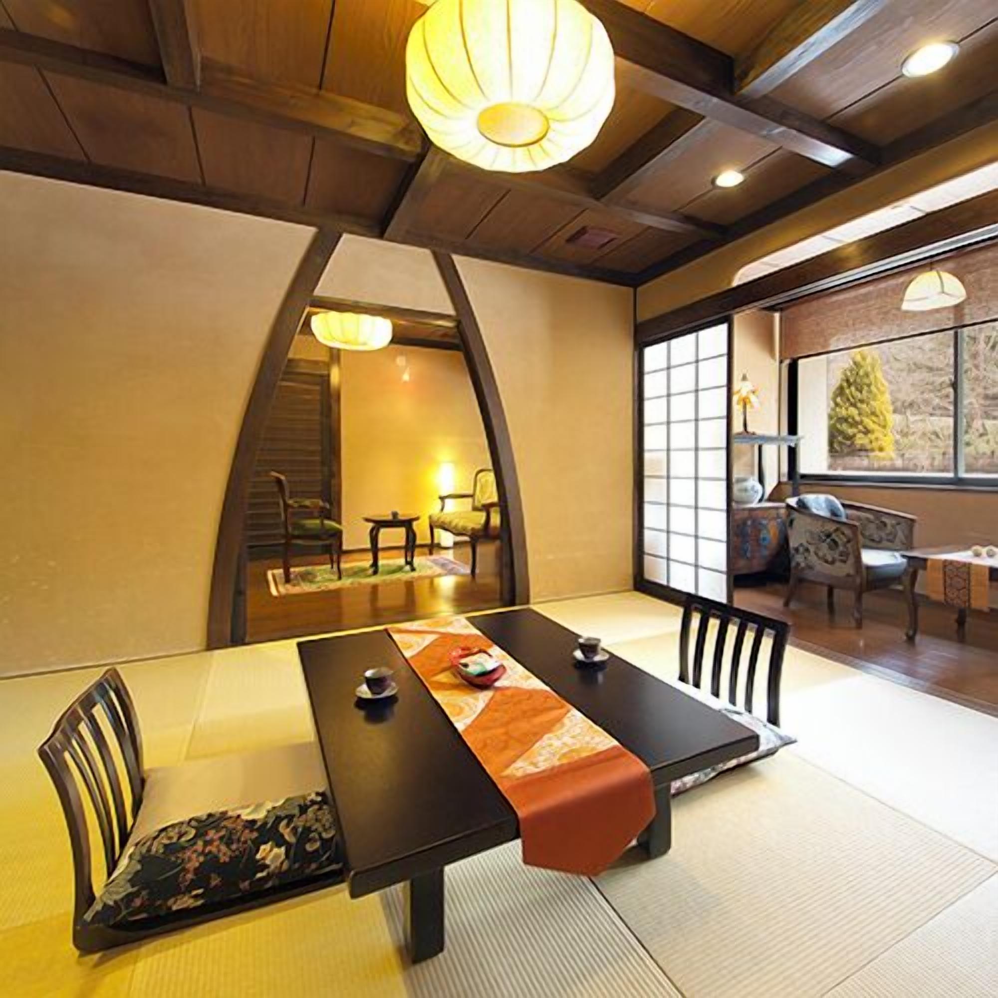 Une pièce de style japonais traditionnel, avec un sol recouvert de tatamis, une table basse et une vue sur l’extérieur.