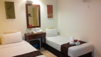 Quarto de hotel com duas camas, uma escrivaninha com telefone, uma cafeteira e um vaso com flores vermelhas.
