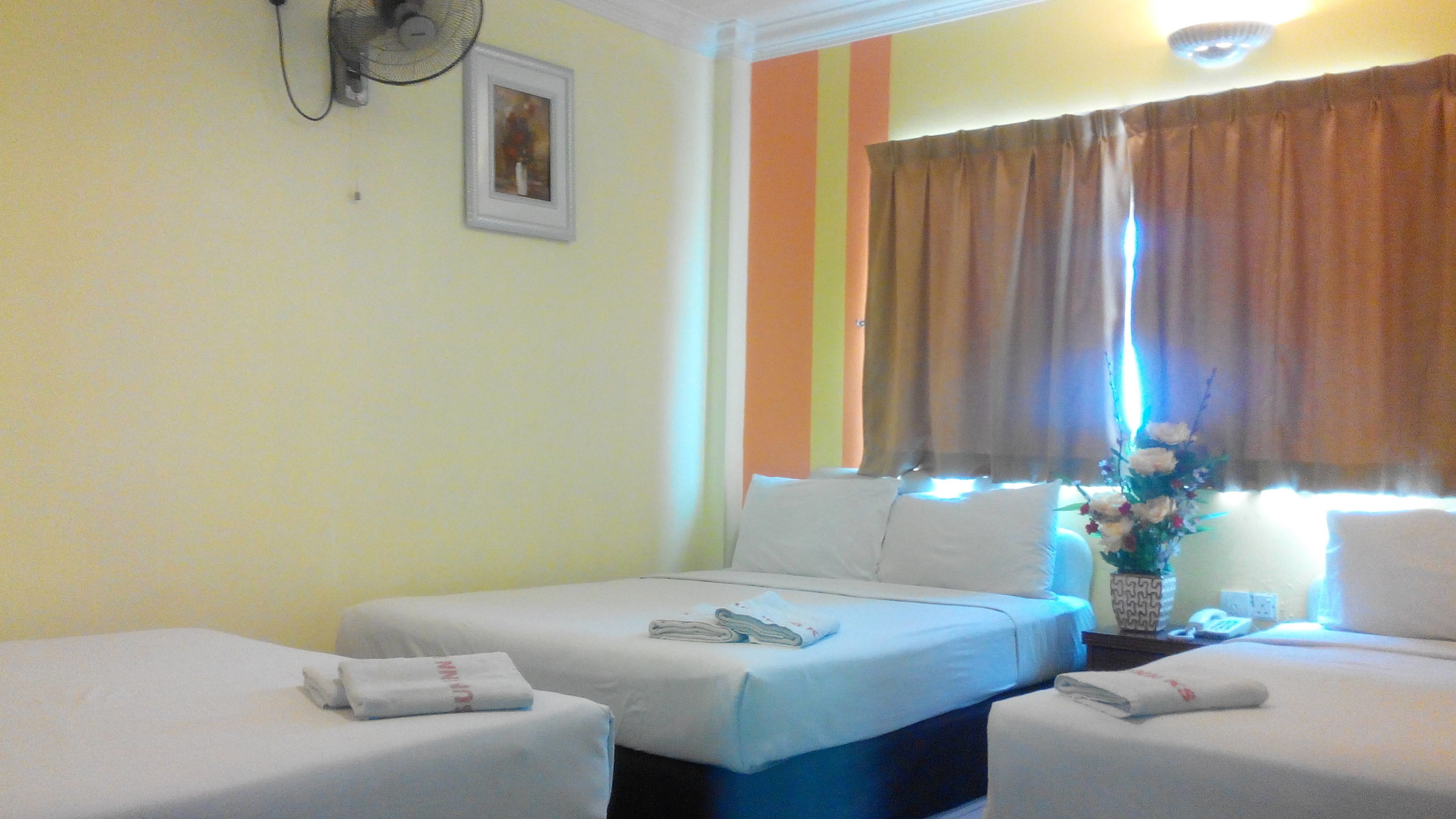 Habitación de hotel con dos camas, un ventilador, un cuadro en la pared y una ventana con cortinas.