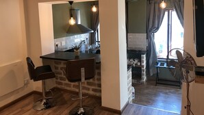 Una cocina moderna con barra, una silla de comedor y un ventilador.