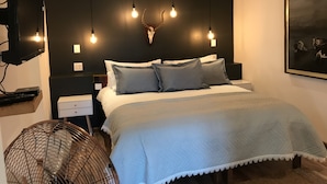 Un dormitorio moderno con cama, mesitas de noche, televisor montado y lámpara de pared.