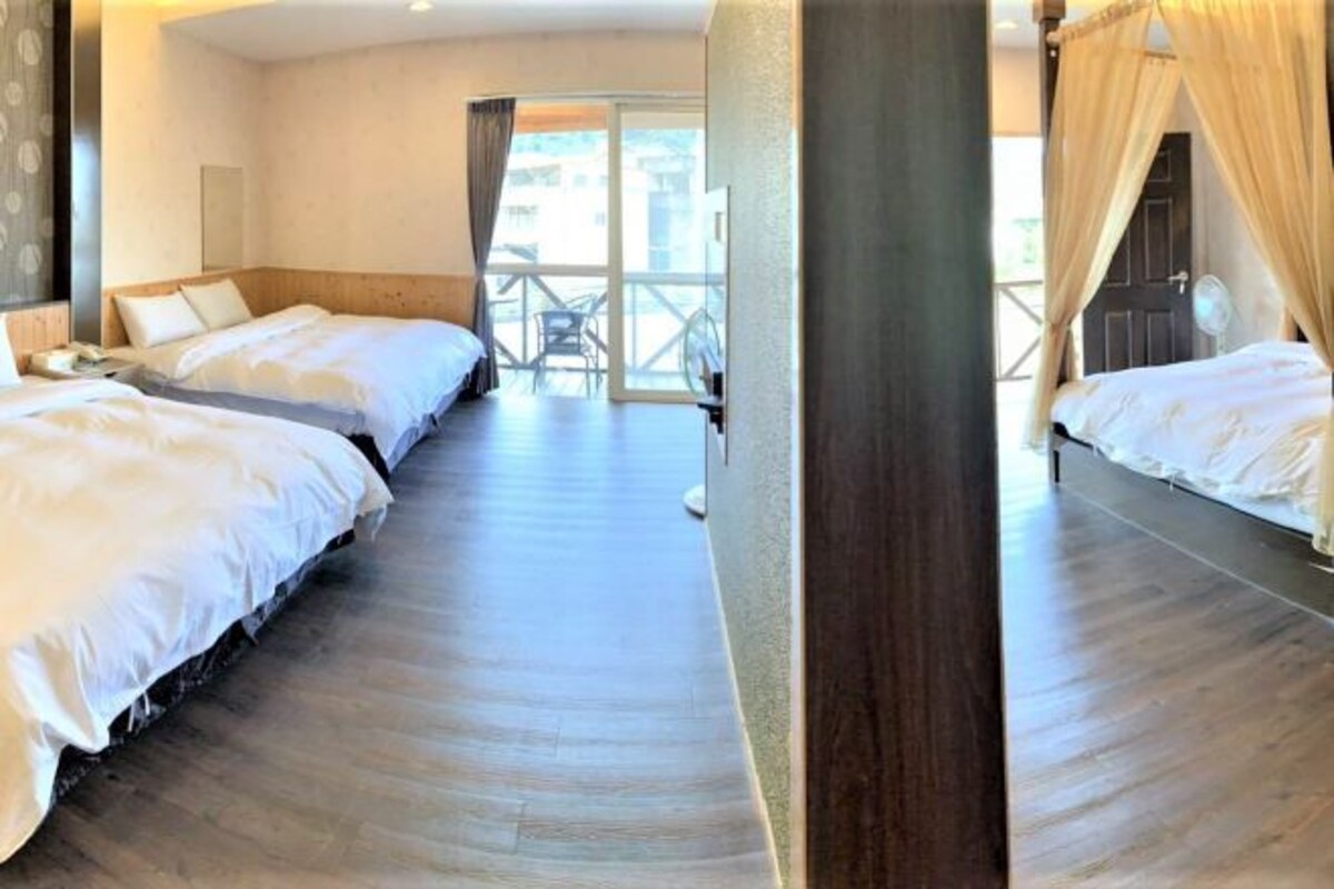 A hotel room with two beds, a balcony, and a large window.