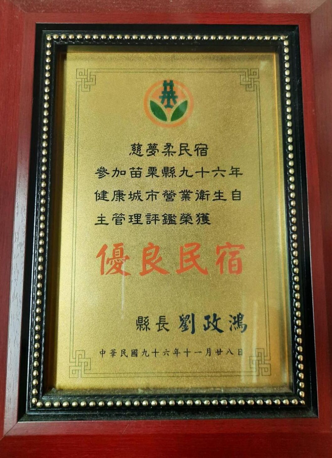 Un certificado enmarcado, con texto y un logotipo, rodeado de una filigrana decorativa.