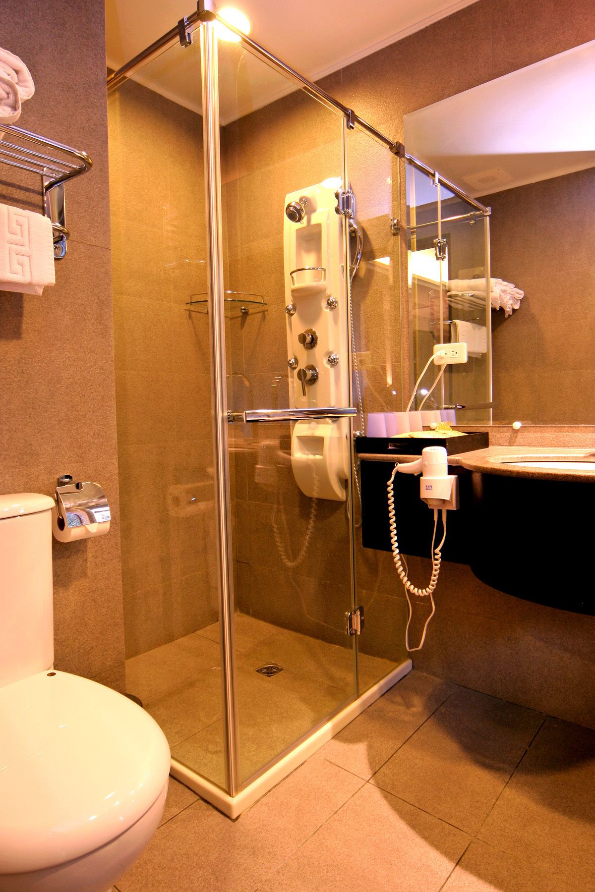 Un baño moderno con ducha de vidrio, inodoro y lavabo con espejo.