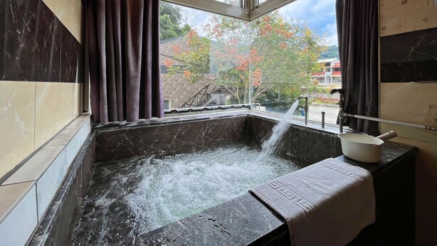 A hot tub with a view of a brick building and trees outside. - Cimengrou Hall (Dahu)