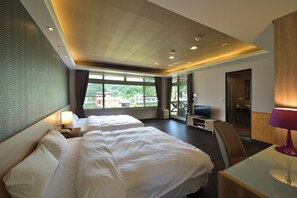 A hotel room with two beds, a desk, a TV, and a view of the city.