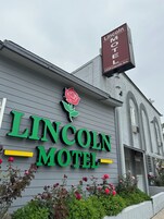 Exterior del motel Lincoln, con un llamativo letrero verde y una decoración de rosas.