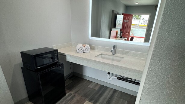 Casa de banho compacta com lavatório, espelho e micro-ondas preto.