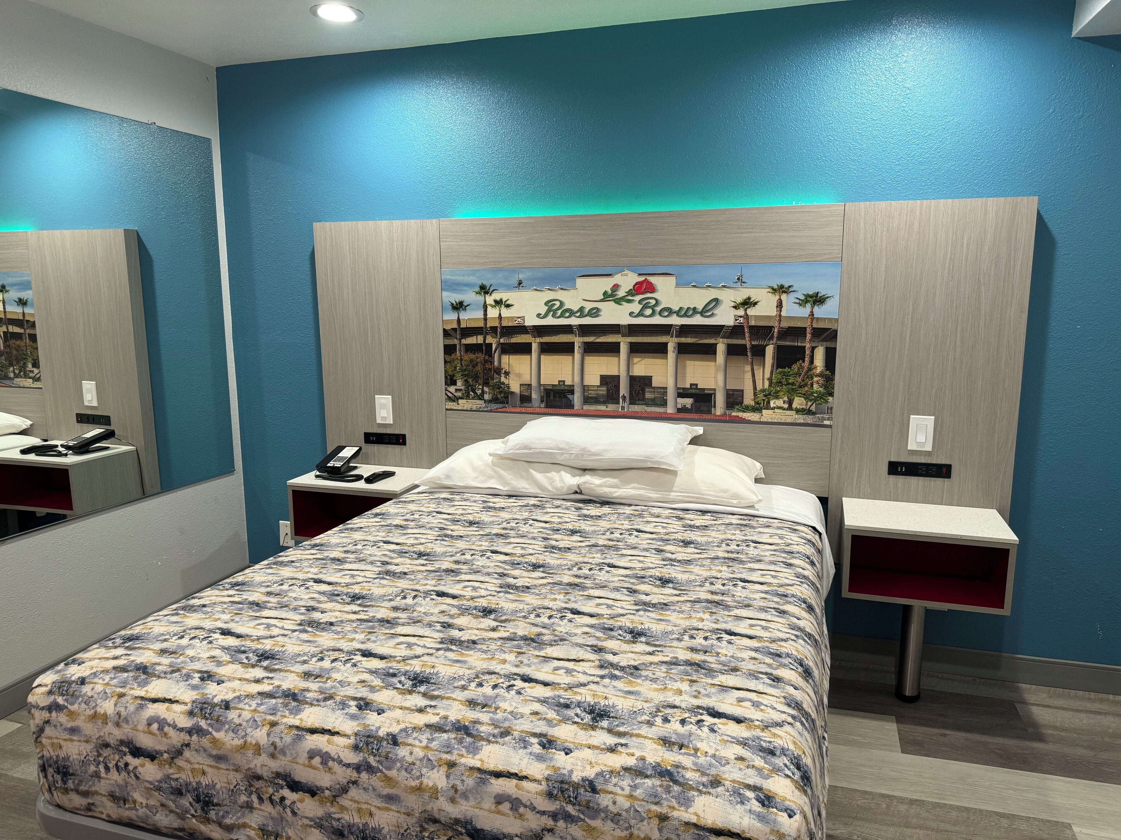 Une chambre d’hôtel avec un grand lit, une table de chevet avec un téléphone et un téléviseur fixé au mur.