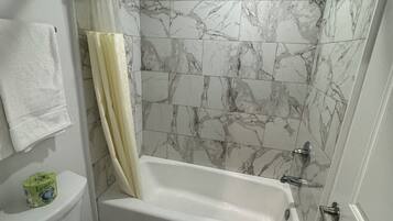 Un baño con bañera, inodoro y zona de ducha.