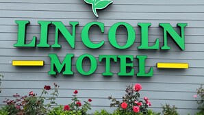 Placa de motel com o nome 'LINCOLN MOTHET' e um símbolo de rosa acima.