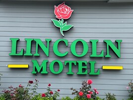 Señal de motel con el nombre 'LINCOLN MOTHET' y un símbolo de rosa encima.