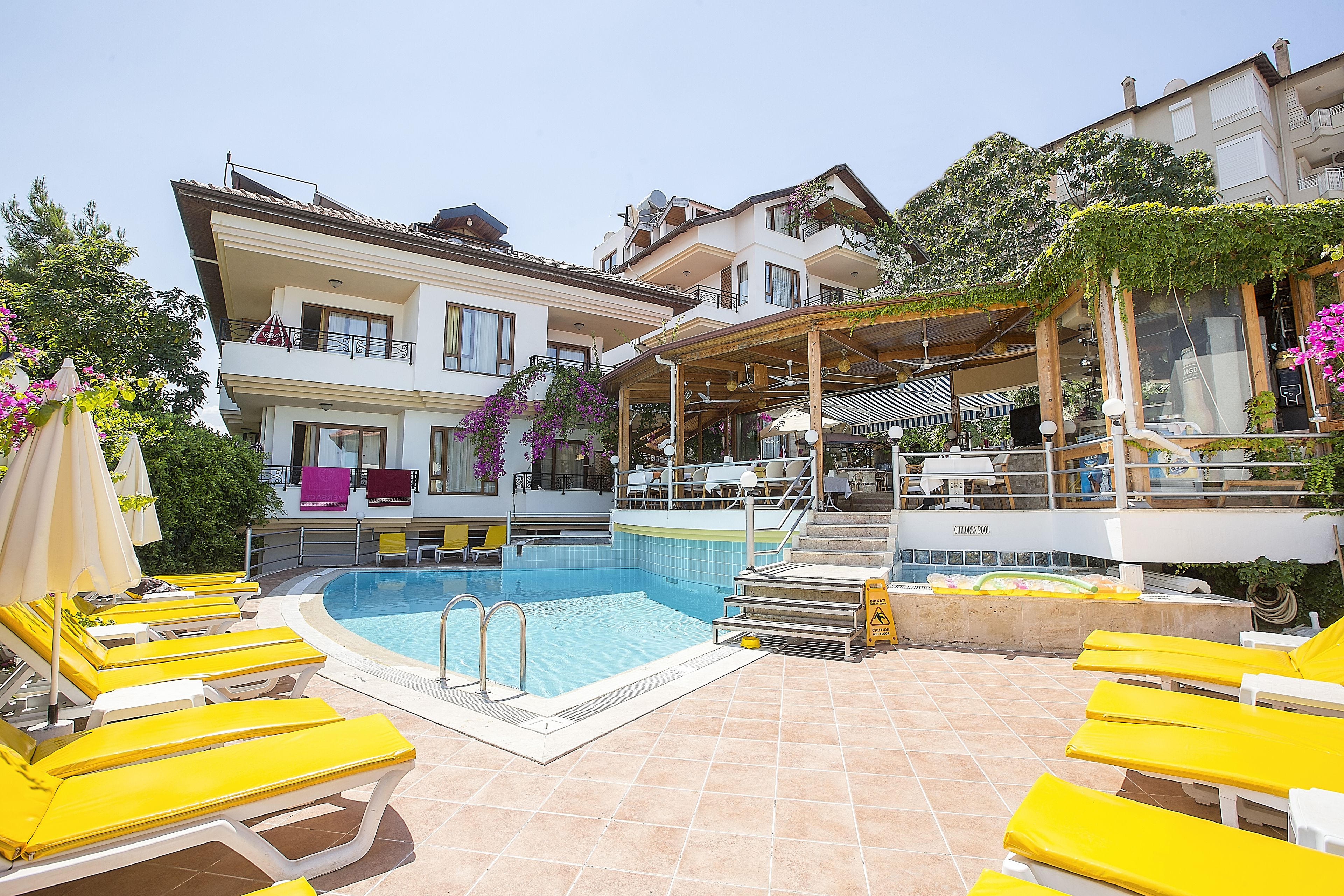 A swimming pool area with yellow lounge chairs, a children's pool, and a covered seating area.