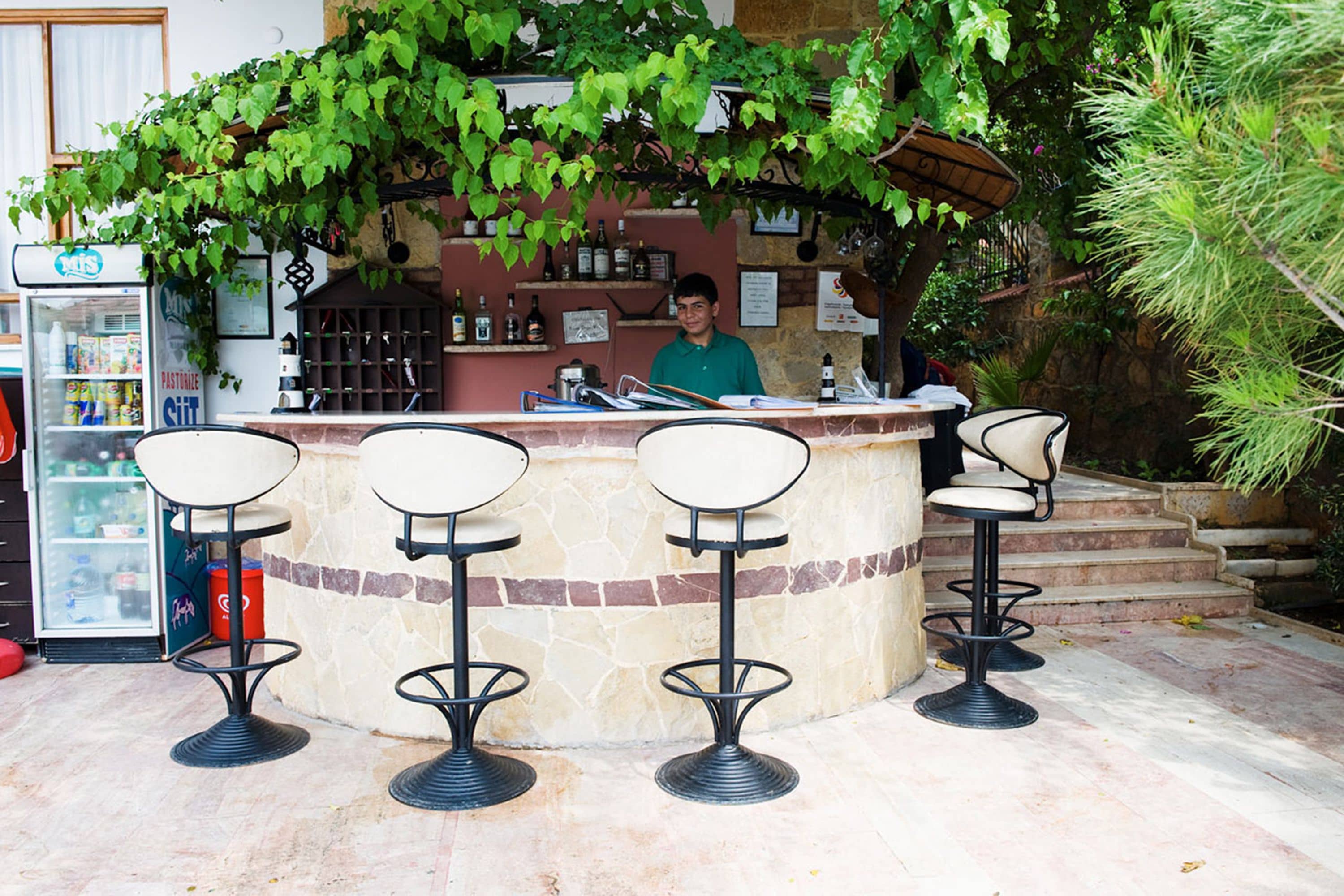 A bar area with a stone counter, four bar stools, and a bartender.
