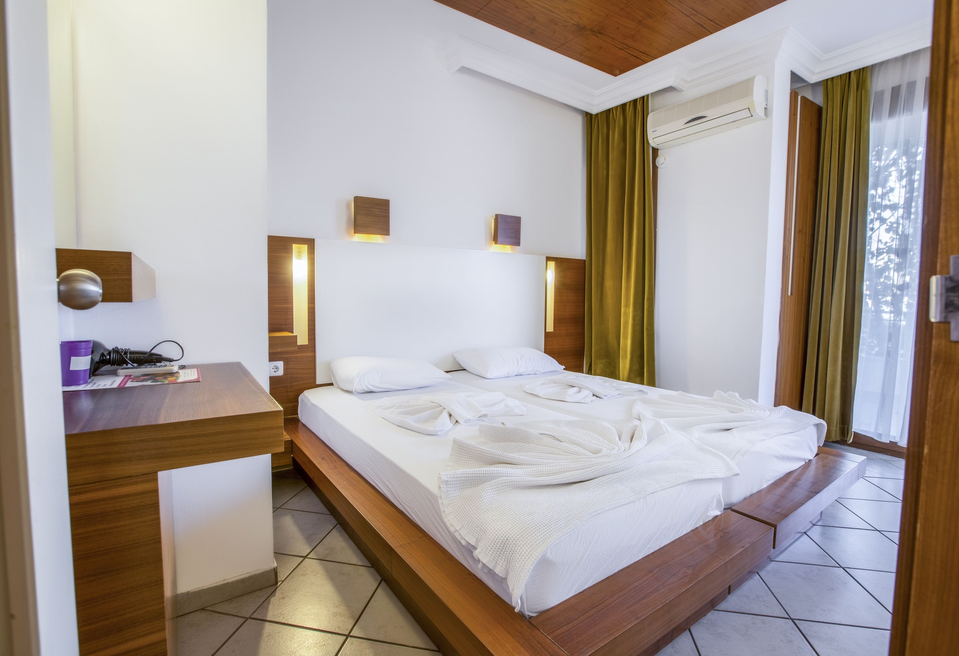 Een moderne hotelkamer met een houten bed, nachtkastjes en wandlampen.
