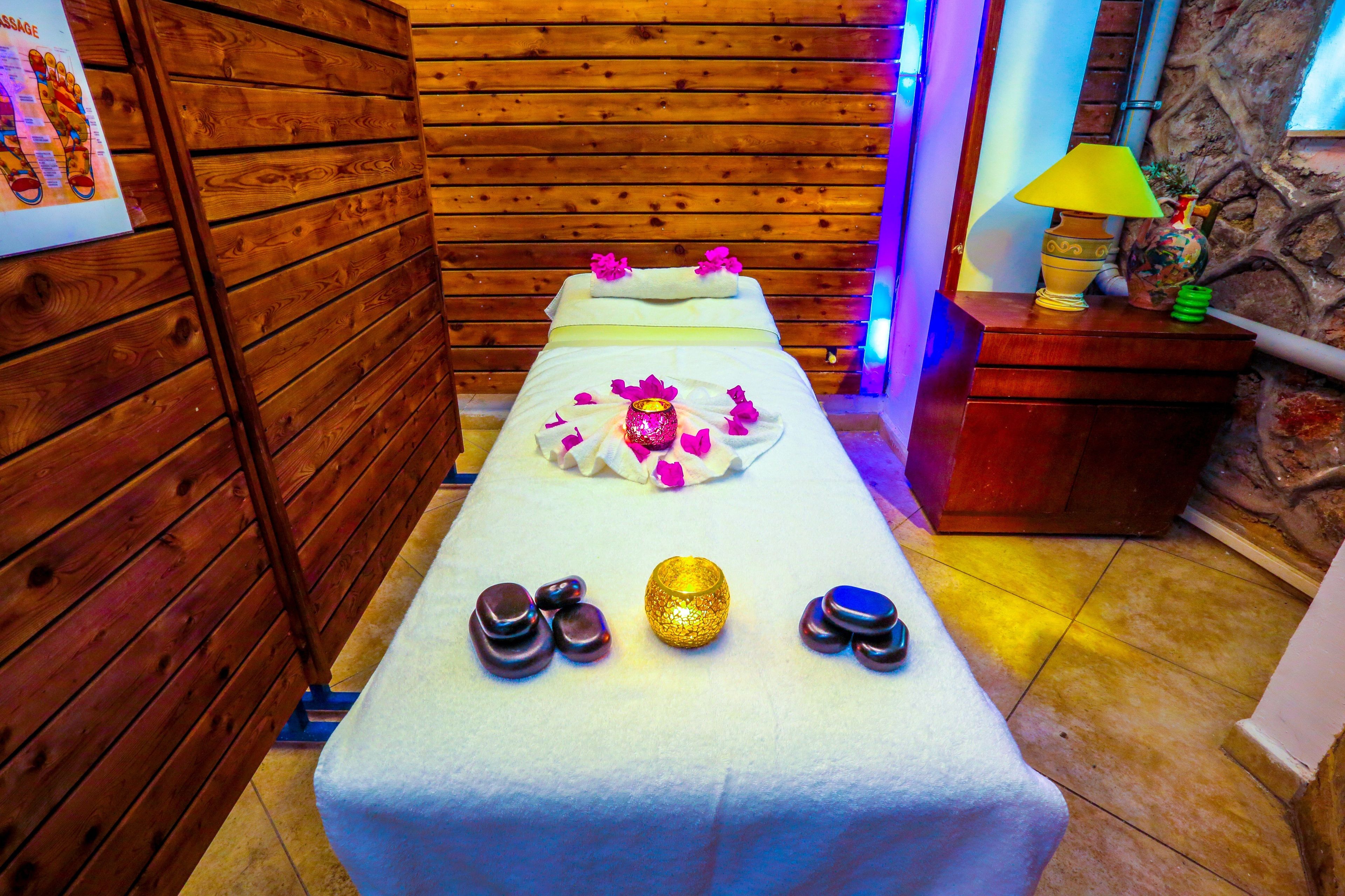 A wooden room with a massage table, a lamp, and a vase.