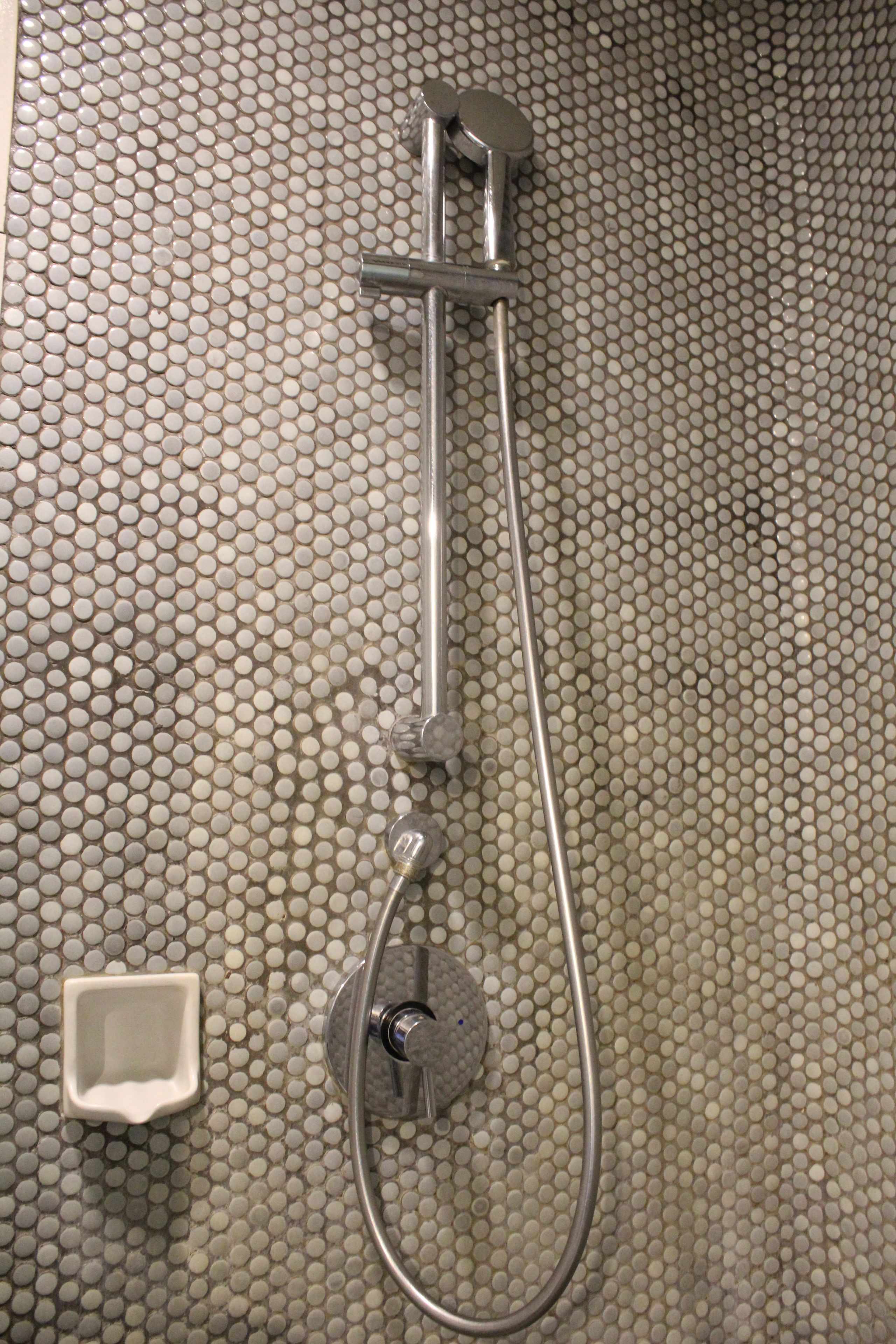 A shower with a handheld showerhead and a wall-mounted faucet.
