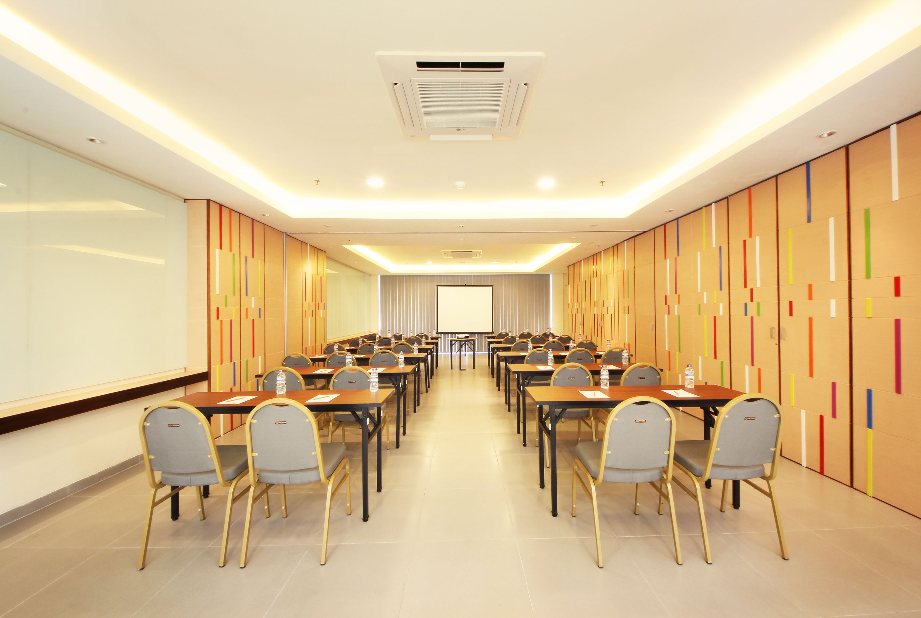 A conference room with multiple tables and chairs, a projector screen, and a whiteboard.