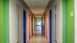 Een lange, smalle gang met deuren aan beide kanten, elk deur voorzien van een nummer.