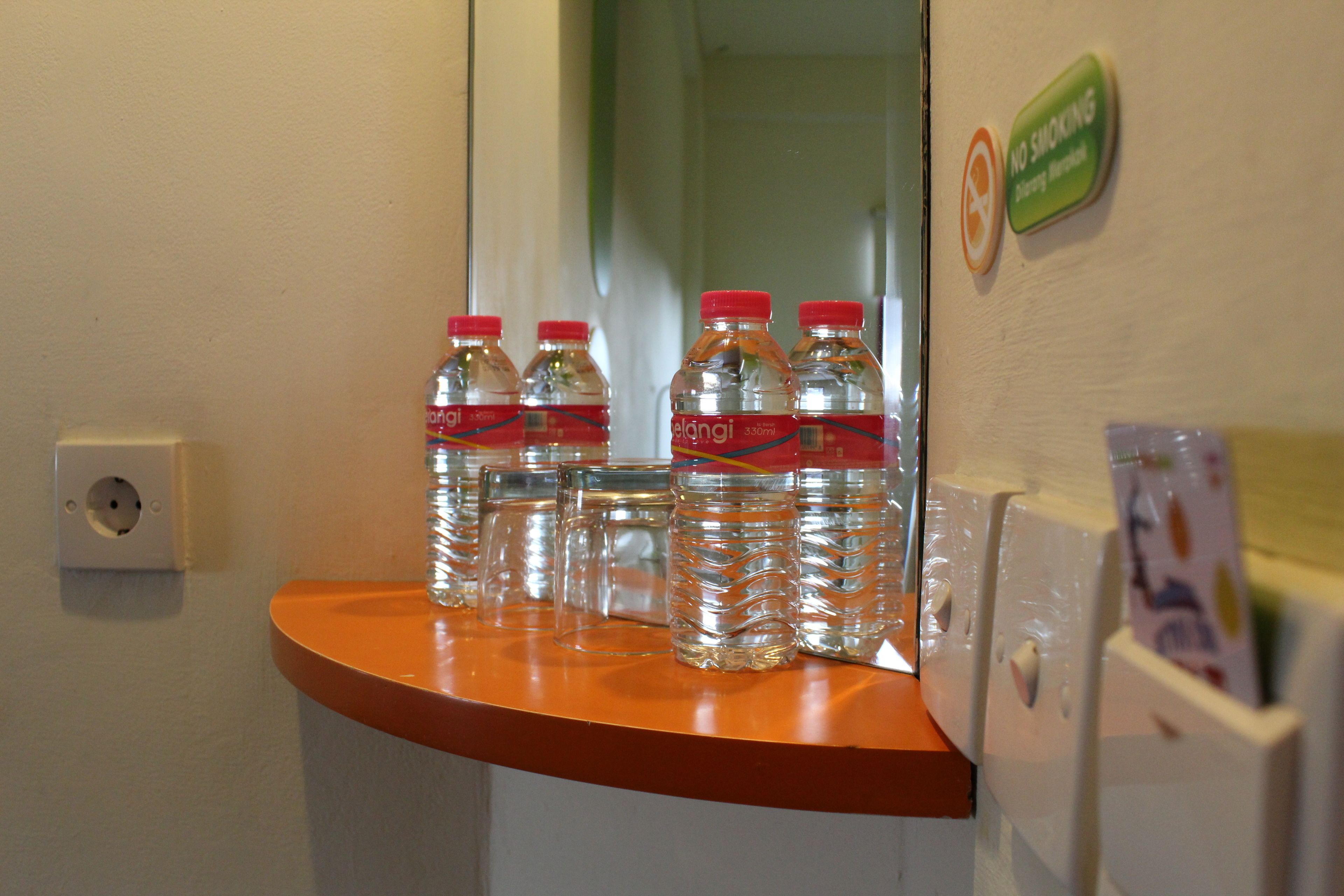 A bathroom counter with water bottles and a no-smoking sign.