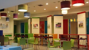 A brightly lit dining area with green and red chairs, tables, and colorful hanging lamps. - POP! Hotel Sangaji Yogyakarta (Yogyakarta)