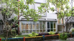 Een modern gebouw met grote ramen, een verzorgde tuin met verschillende planten en een verhard pad.