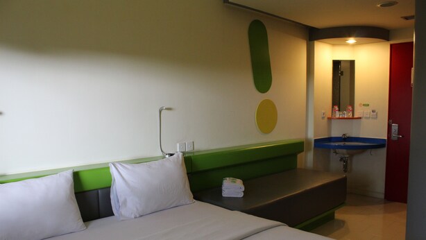 A hotel room with a bed, a green headboard, a blue sink, and a red door. - POP! Hotel Sangaji Yogyakarta (Yogyakarta)