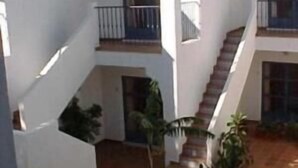 A multi-level courtyard with white walls and terracotta flooring, featuring a central staircase and potted plants. - Hotel Atalaya (Nijar)