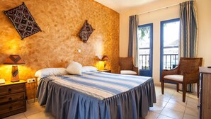 A bedroom with a large bed, two bedside tables with lamps, a chair, and a desk. - Hotel Atalaya (Nijar)