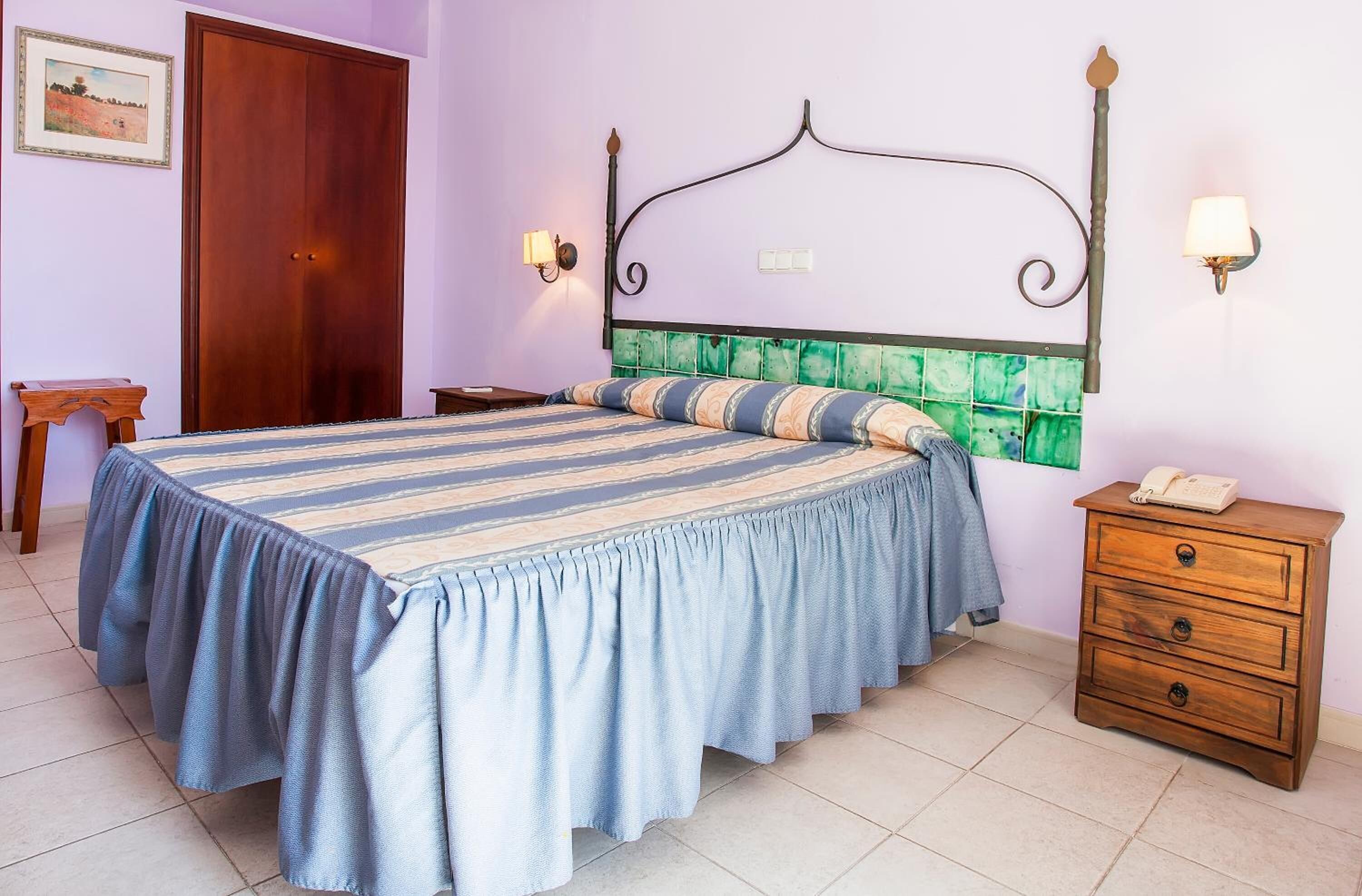 Une chambre à coucher avec un lit, une table de chevet, une commode en bois et une porte.