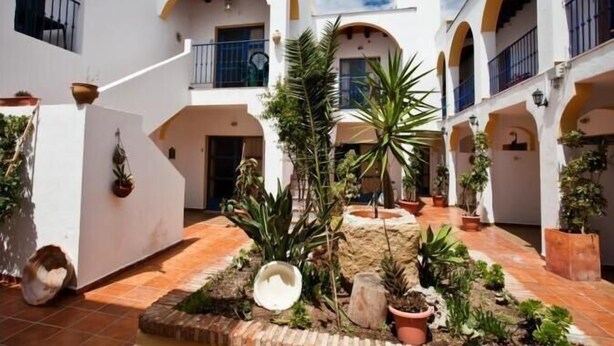 A courtyard with white walls, arches, and potted plants. - Hotel Atalaya (Nijar)