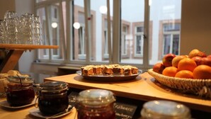 A breakfast setup with a fruit basket, jam jars, and a tray of pastries.