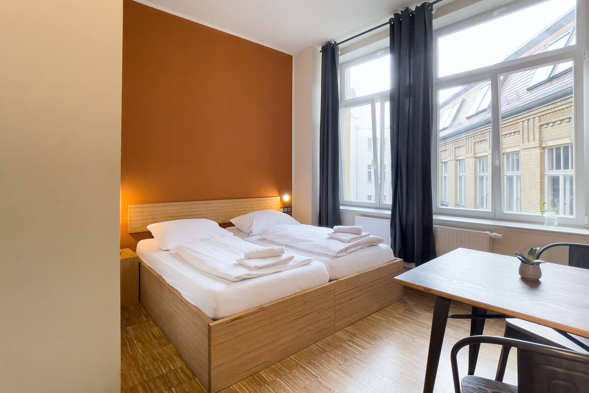 A hotel room with a wooden bed, a table, and a chair.