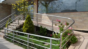 A modern building with a staircase, metal railings, and a garden with various plants and flowers. - Florida del Inca Hotel (Cusco)