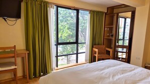A bedroom with a large bed, a desk, a chair, and a TV mounted on the wall. - Florida del Inca Hotel (Cusco)