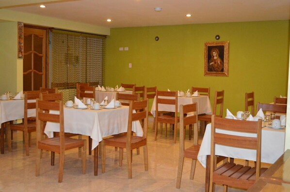 A dining area with multiple tables and chairs, each set with white tablecloths and napkins. - Florida del Inca Hotel (Cusco)